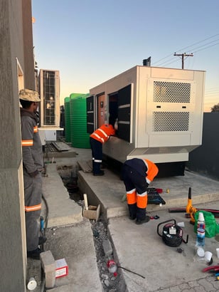 a group of technicians working on a stand-by generator in front of a building