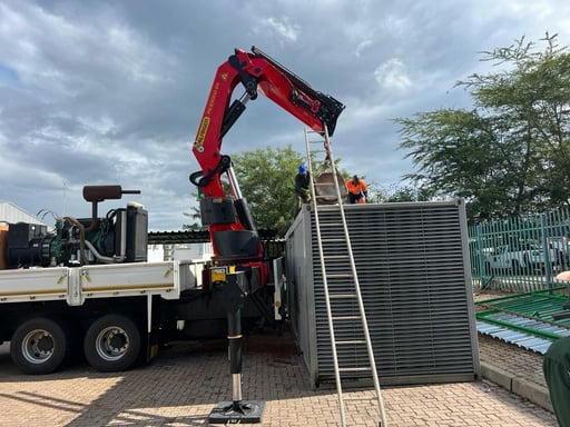 a crane is lifting a stand-by generator off of a truck